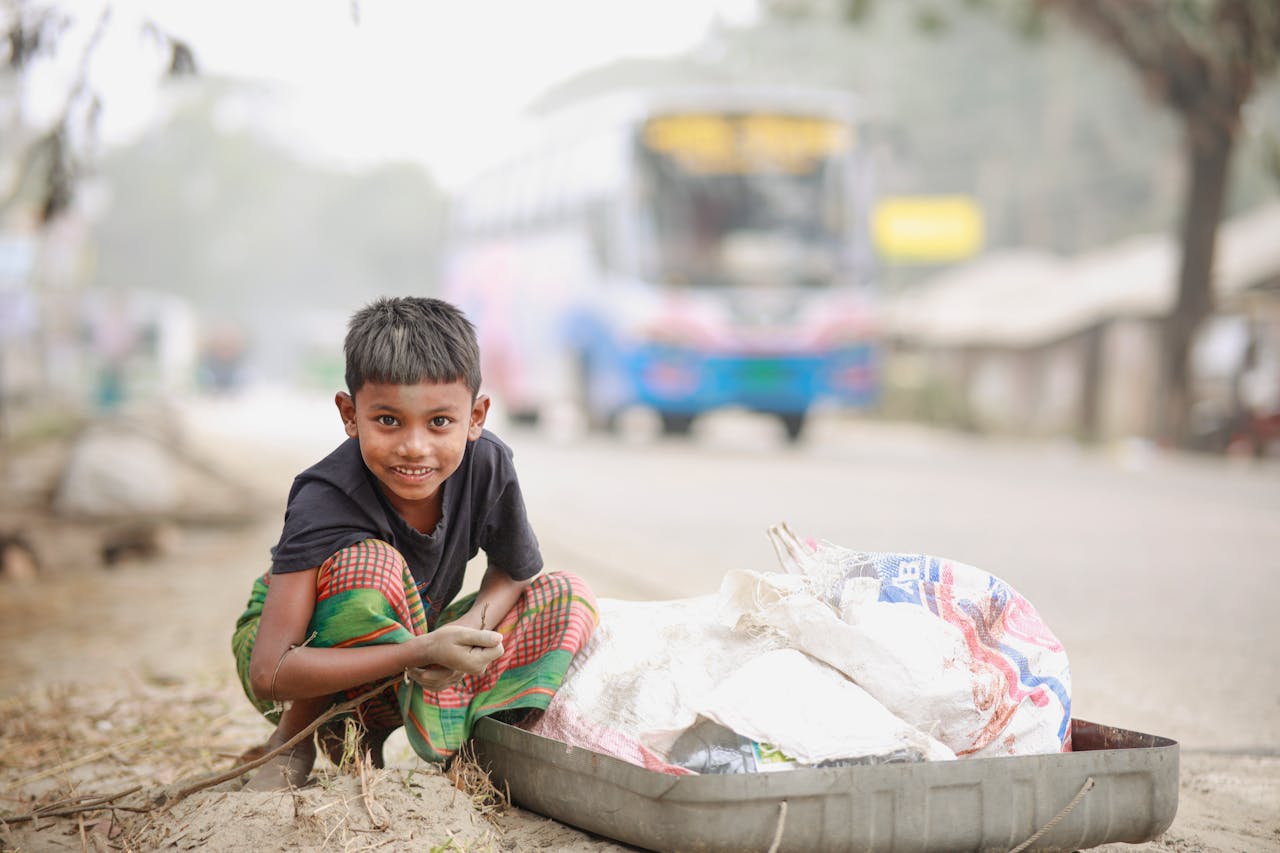 A cheerful child in traditional clothing gathers recyclable materials on a bustling road.